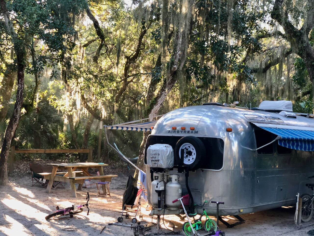 Campsite under moss-draped oaks, awning out